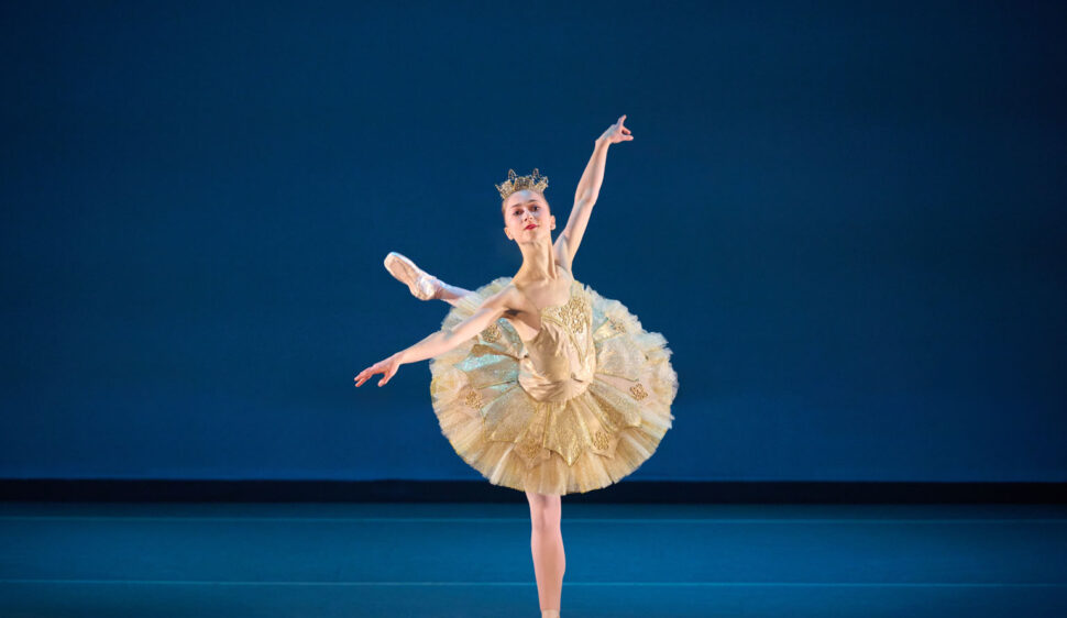 Ballet Eclectica Ballerina on pointe in back attitude wearing gold tutu and crown
