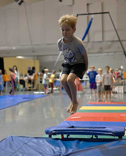 Camper in circus camp jumping off trampoline